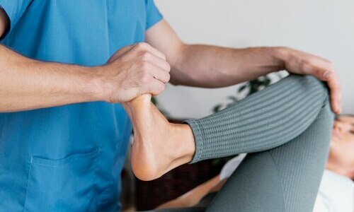 medico osteopata comprobando movimiento pierna paciente femenino